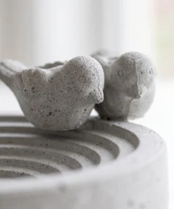 Detail van de vogelfiguren op het betonnen vogelbad